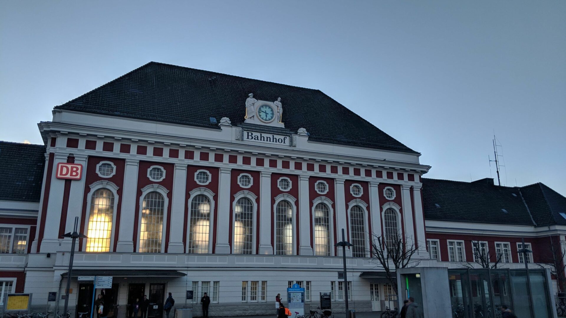 Außenansicht des Bahnhofs Hamm. Das Gebäude ist ein altes Bau mit hocen Fenstern und einer alten Bahnhofsuhr in der Mitte des Gebäudes.